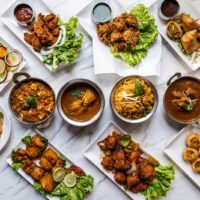 An overhead view of a variety of Indian dishes presented on white plates, highlighting vibrant colors and rich textures.