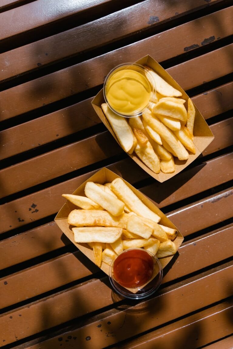 Golden French fries served with ketchup and mustard on a wooden bench. Perfect for fast food themes.
